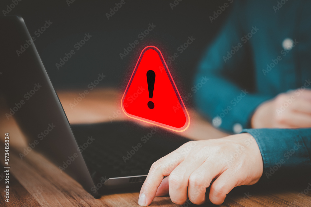 Wall mural adult man using a computer laptop with triangle caution warning sign for notification error. concept