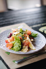 Fresh salad with salted red fish and nuts on wooden table