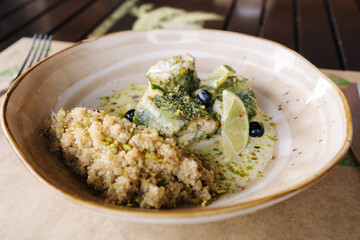 Stuffed fish with a creamy sauce and white cinema as a side dish. Wooden table