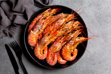 Top view of giant argentinian red prawns, grilled. Black plate. Dark grey background. - obrazy, fototapety, plakaty