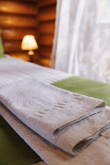 Fototapeta na wymiar Hotel room in a wooden house. Authentic and stylish interior. A folded towel on the bed for visitors