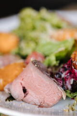 Macro photo of warm salad with veal and apricots. Delicious food in restaurant. Wooden table