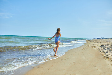 Happy, joyful little girl run on the beach