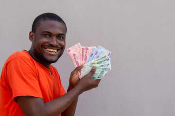 Excited african businessman holding lots of cash, new currency