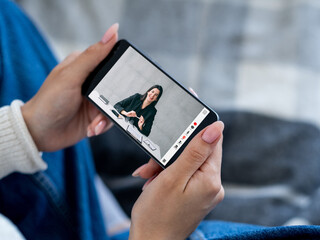 Video call. Mobile chat. Distance communication. Female hands holding smartphone with cheerful business woman on screen on free space background.