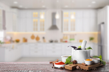Mortar and different spices on wooden table in kitchen. Space for text