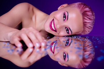 Futuristic vivid portrait of young woman model lying naked on glossy mirror covered sparkling drops cosmetics promo