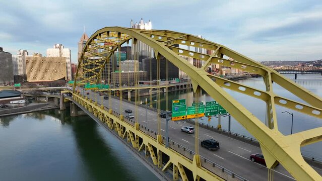 Fort Pitt Bridge in Pittsburgh Pennsylvania spans over Monongahela River. Sun shines on PPG glass castle skyscraper on skyline. Aerial establishing shot.