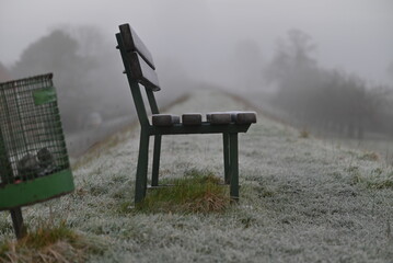 Parkbench and a dustbin on a dike as a closeup