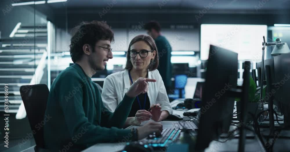 Fototapete Two Young Colleagues Working on Computers and Talking at a Workplace. Female and Male Software Developers Discussing a Solution for Their Collaborative Artificial Intelligence Project