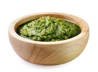 Pesto sauce in a wooden plate on a white background. Isolated