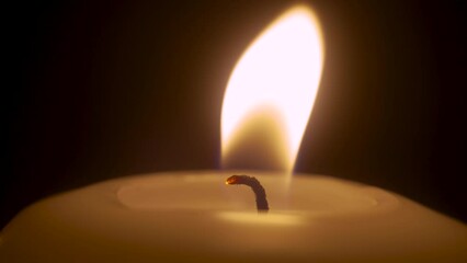 Single white candle burning and extinguish by wind blowing. Isolated candlelight with dark background. Paraffin candle with yellow shades burns. Lifestyle remembrance celebration religious