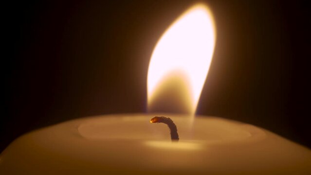 Single white candle burning and extinguish by wind blowing. Isolated candlelight with dark background. Paraffin candle with yellow shades burns. Lifestyle remembrance celebration religious