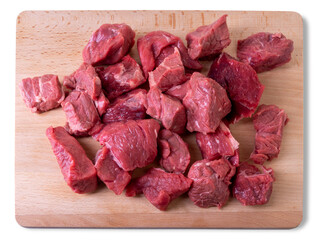 Raw beef diced for stew on wooden cutting board in top view