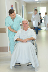 Obraz premium nurse pushing senior patient in wheelchair along corridor