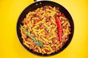 stewed pasta with meat in a frying pan