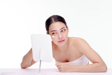 Beautiful Asian woman sitting in front of a mirror. woman applying cream skin care treatment. Advertisement for skin cream, anti-wrinkle cream, baby face