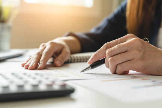 Women business people use calculators to calculate the company budget and income reports on the desk in the office.