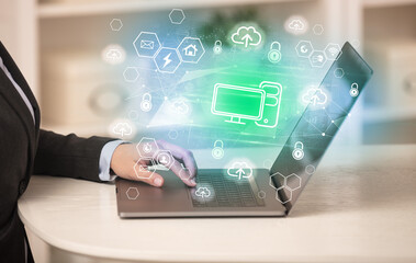 Hands working on laptop with digital icons