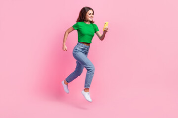 Full length photo of shiny pretty lady dressed green t-shirt jumping high typing modern device isolated pink color background