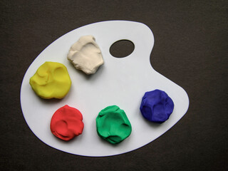 Colourful plasticine on the pallet on a dark background