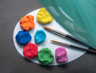 Colourful plasticine on the pallet on a dark background