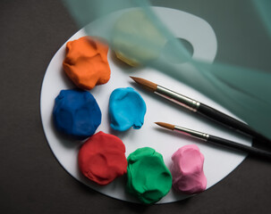 Colourful plasticine on the pallet on a dark background