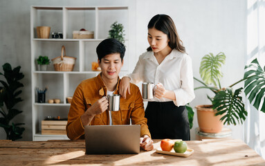 Two Asian business workers talking on the smartphone and using laptop at the home office.