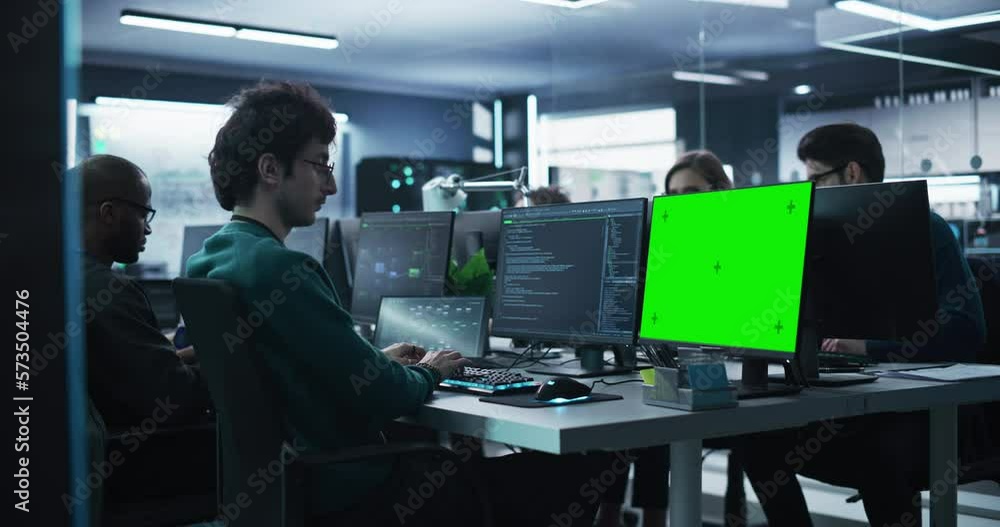 Poster Team of Talented Young Professionals Working in a Technological Research and Development Agency. Young Software Programmer Working on a Computer with Green Screen Mock Up Display