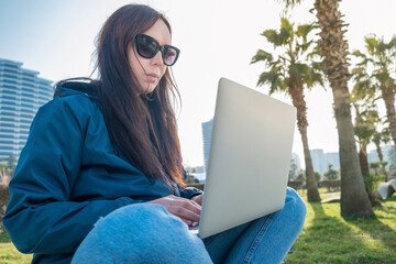 Young woman freelancer or digital nomad working remotely using laptop for communication, chat online