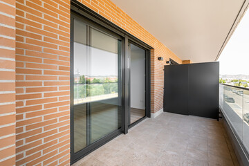 Large entrance balcony door made of black plastic with a sliding system. Terrace with marble floor...