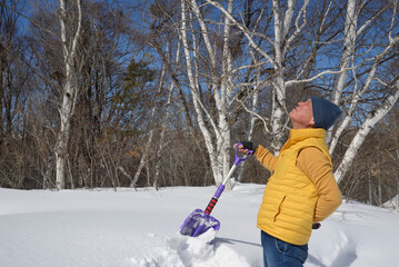 Fototapeta na wymiar 雪国で除雪をして疲労している日本人シニア男性
