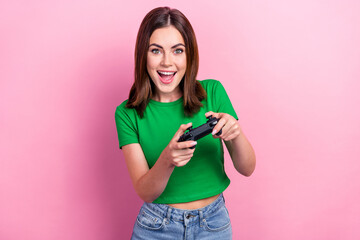 Portrait of overjoyed cheerful girl hands hold controller play video games isolated on pink color...