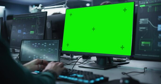 Close Up of a Software Developer Working on a Desktop Computer with Green Screen Mock Up Display. Specialist Typing on Keyboard, Coding and Implementing a New Technical Feature, Working in an Agency