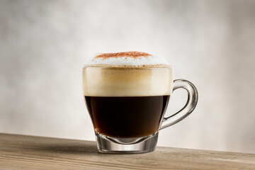 Cappuccino in glass cup on wooden table