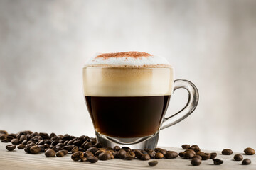 Cappuccino in glass cup on wooden table with coffee beans.