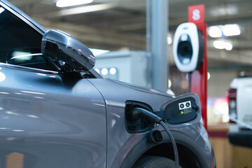 Fototapeta premium Power cable pump plug in charging power to electric vehicle EV car with modern technology UI control information display, car fueling station connected power cable alternative sustainable eco energy