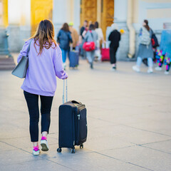Unrecognizable girl walking at train station with suitcase, travel and tourism