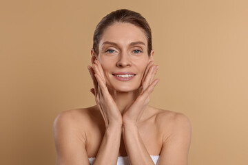 Woman massaging her face on beige background