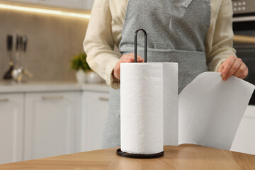 Woman using paper towels in kitchen, closeup. Space for text