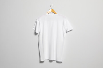Hanger with white t-shirt on light wall. Mockup for design