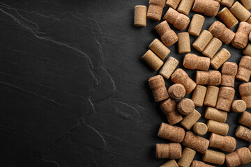 Wine bottle corks on black table, flat lay. Space for text