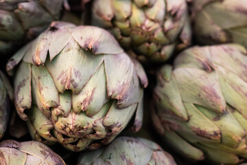 Close-up of bunch of fresh artichokes in the market top view, vegetable background.
