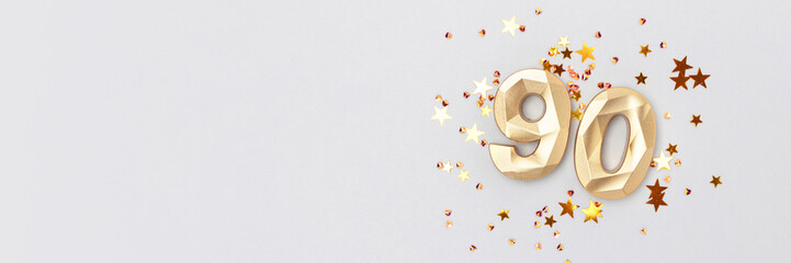 Banner with golden number 90 and shimmer stars confetti on a blue background. Festive composition...