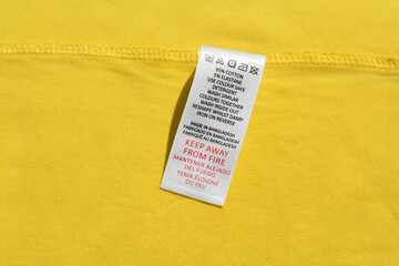 Clothing label on yellow garment, top view