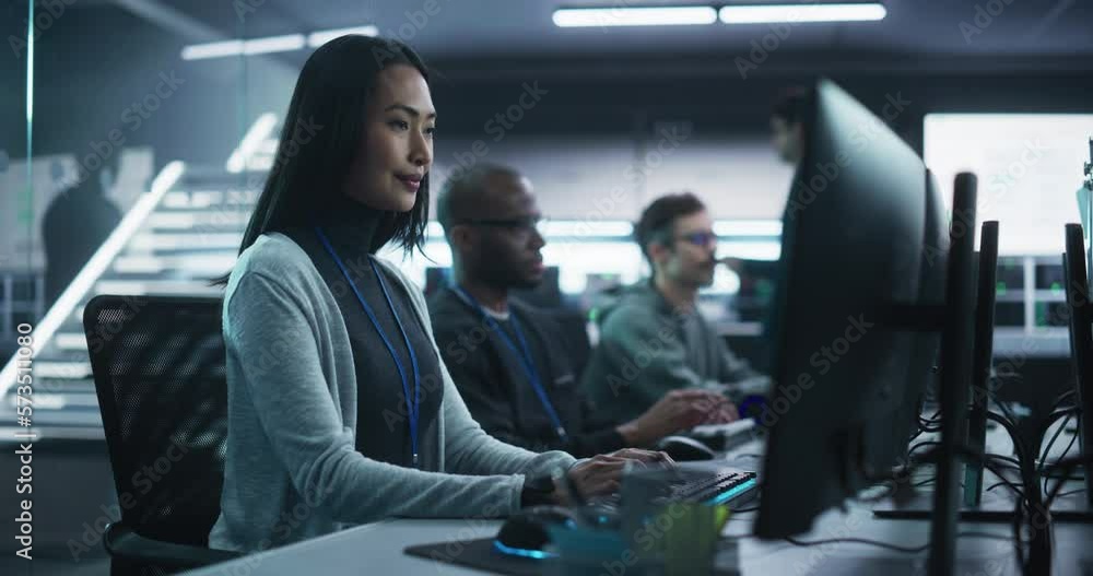 Poster young asian female software developer working on computer together with diverse creative colleagues.
