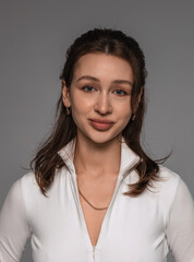 Portrait of a beautiful young girl on a gray background in the studio with light makeup and accessories