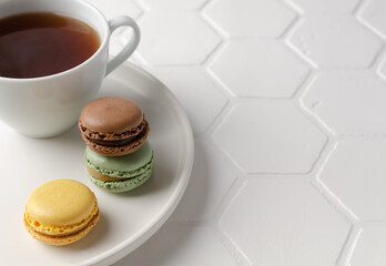 Colorful french macarons or macaroons (almond cookies) with a cup of tea on the  white background. Copy space for text