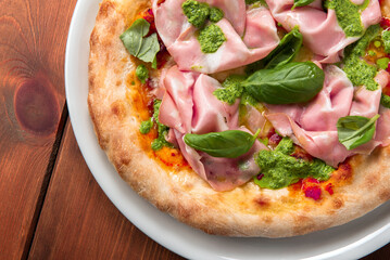 Deliziosa pizza gourmet condita con mortadella e pesto, cibo italiano 