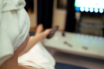 Fototapeta premium selective focus on young girl watching television relaxed after showering, beauty routine, at home